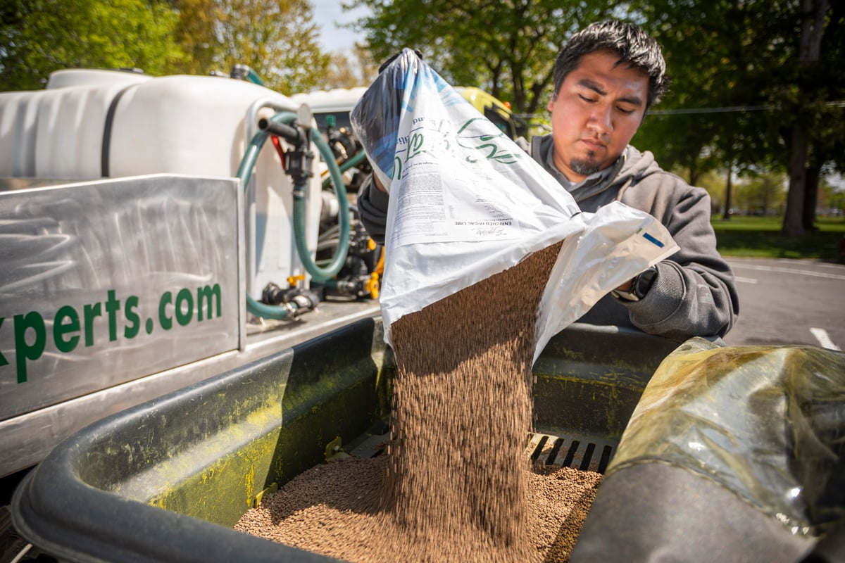 lawn care expert pours limestone into spreader