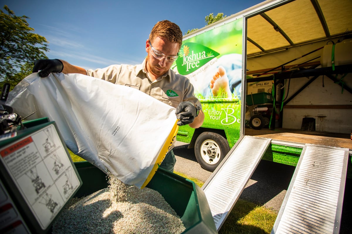 lawn care expert pours fertilizer into spreader