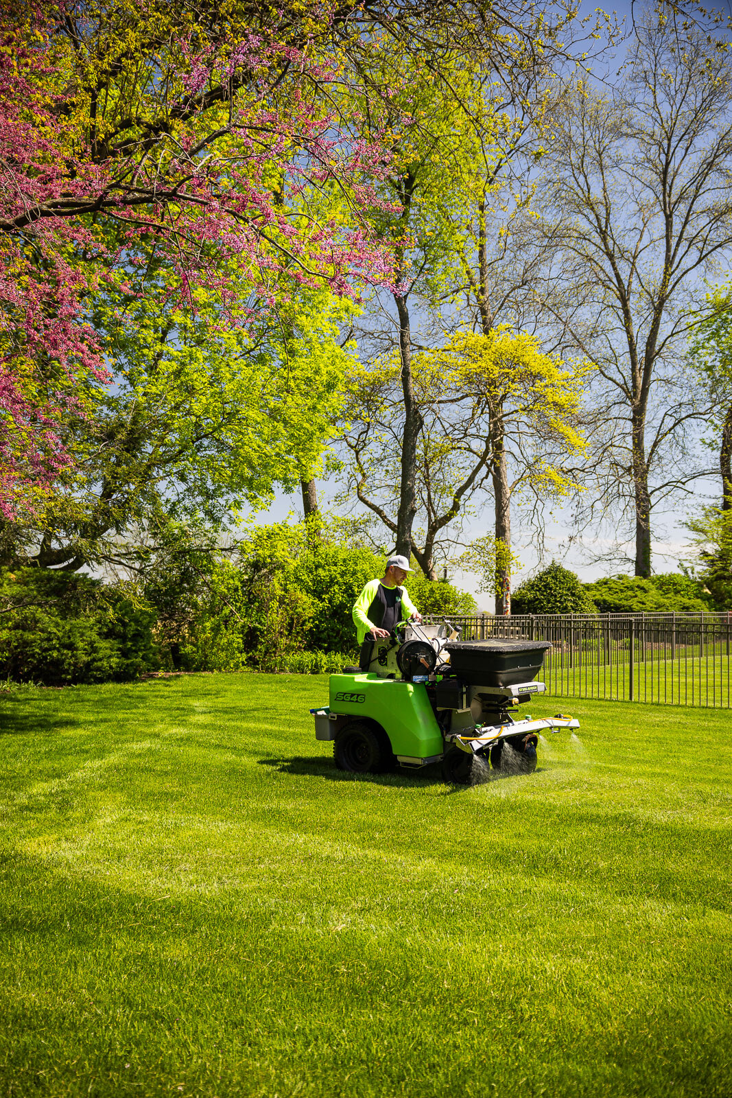 lawn care technician operating spreader in backyard 3