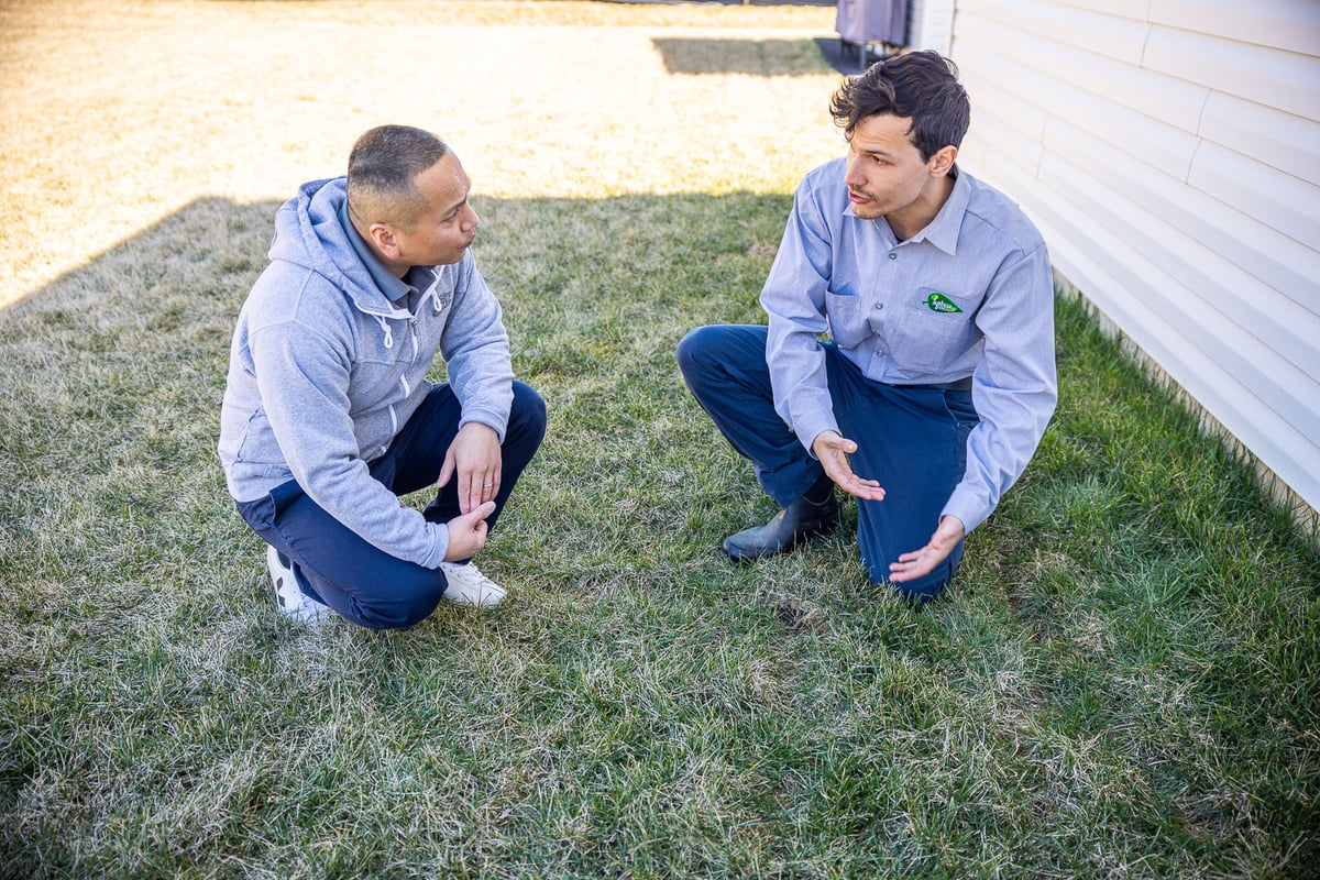 lawn care technician and customer inspect grass