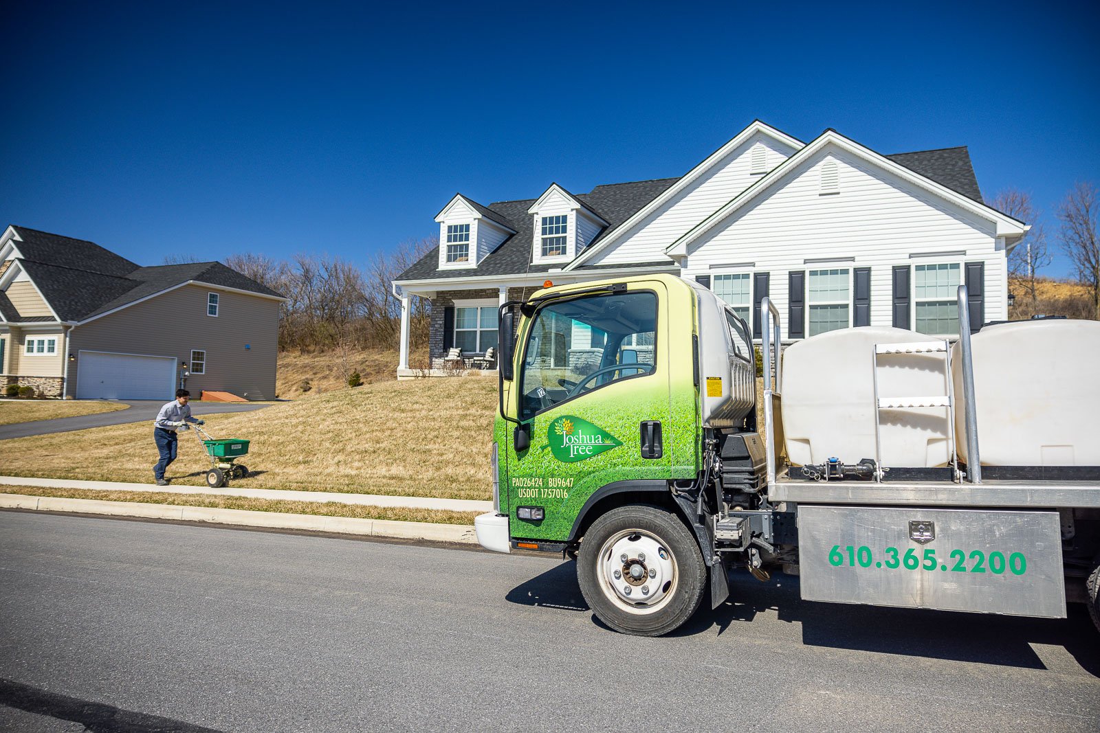 lawn care technician spreads fertilizer with pre-emergent weed control