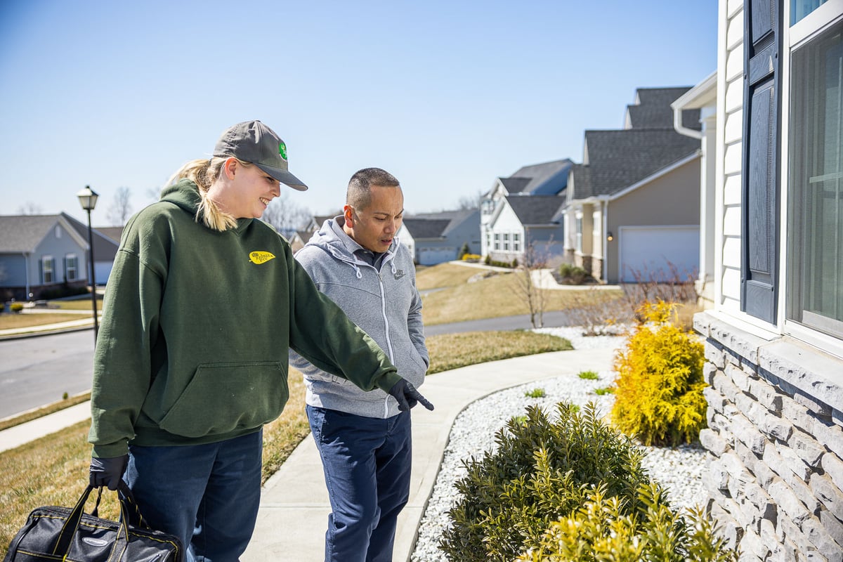 pest control technician inspects home with customer