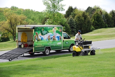 Joshua Tree lawn care truck and technician applying fertilizer