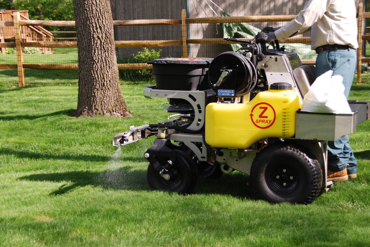 lawn care team spreads liquid weed control