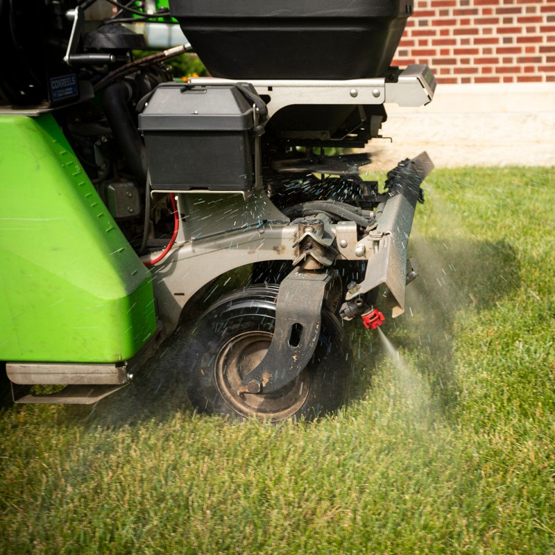 technician sprays fungicide on lawn