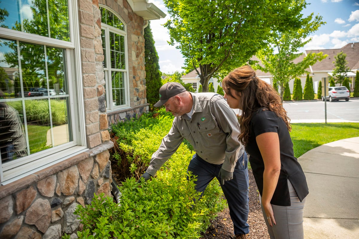 pest control technician inspects home with customer