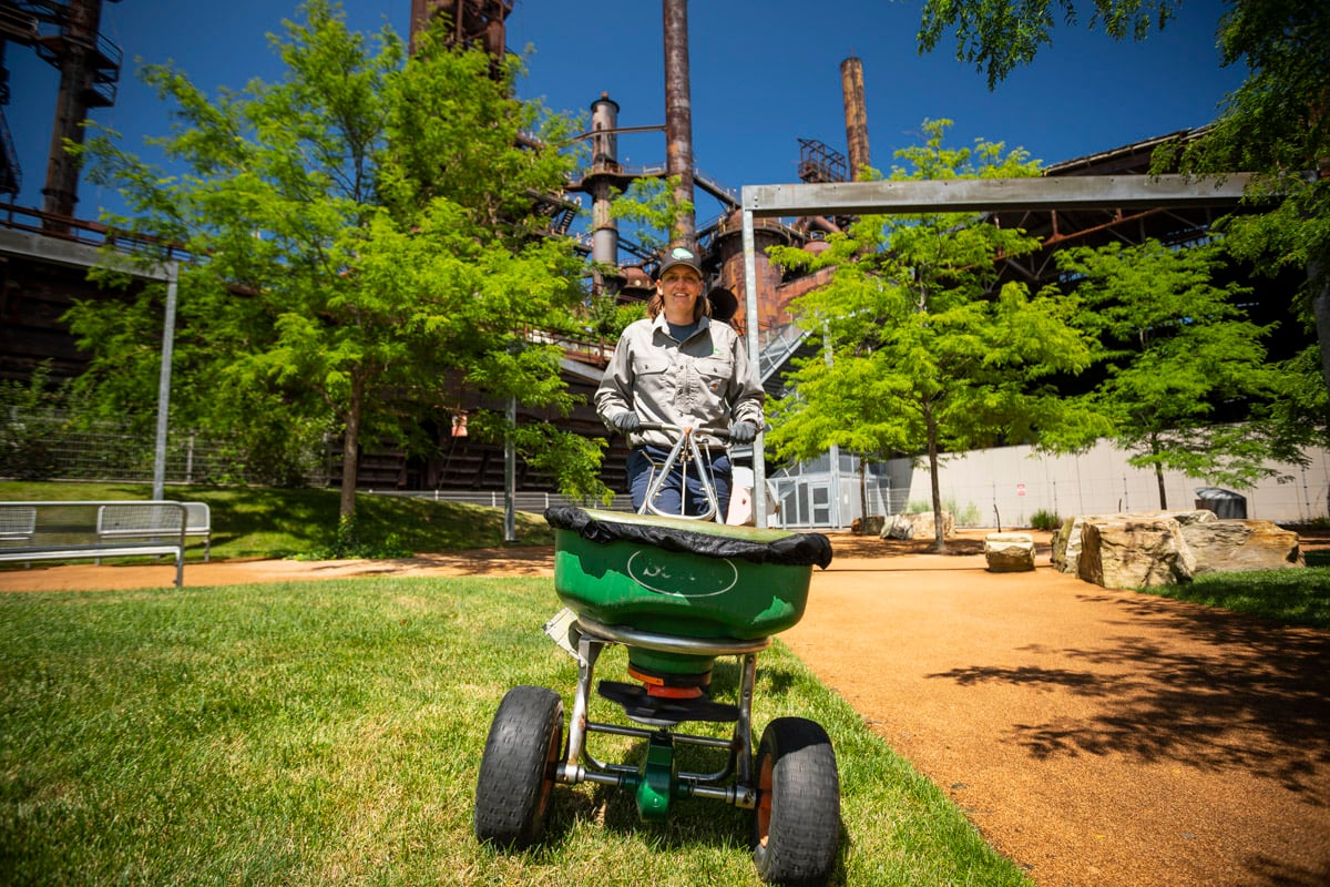 Trained lawn care technician applying granular fertilizer