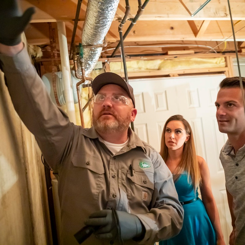 pest control expert inspects basement with homeowner